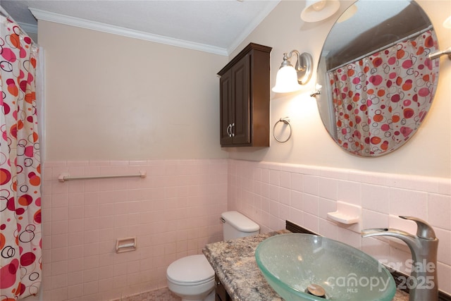 bathroom featuring ornamental molding, a wainscoted wall, tile walls, and toilet