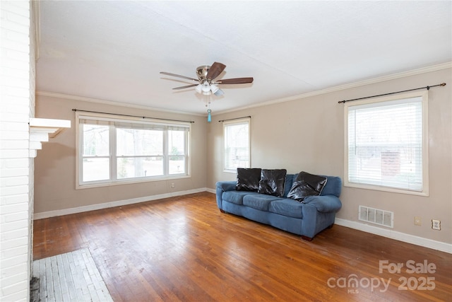 living room featuring baseboards, visible vents, wood finished floors, and ornamental molding