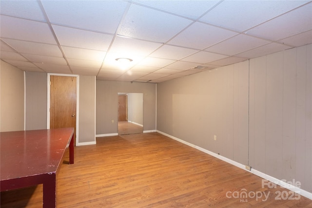 empty room with a drop ceiling, baseboards, and wood finished floors