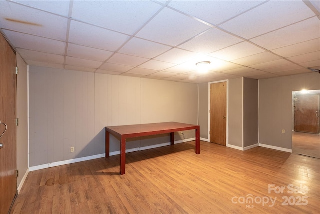 basement featuring a paneled ceiling, baseboards, and wood finished floors