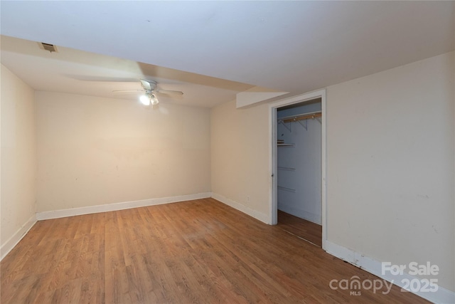 unfurnished bedroom with a closet, ceiling fan, baseboards, and wood finished floors