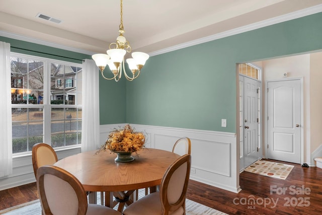 dining area with crown molding, wood-type flooring, and a notable chandelier