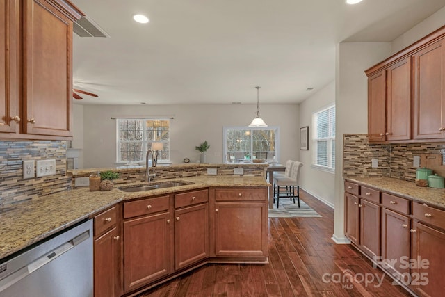 kitchen with pendant lighting, sink, dishwasher, dark hardwood / wood-style floors, and light stone counters