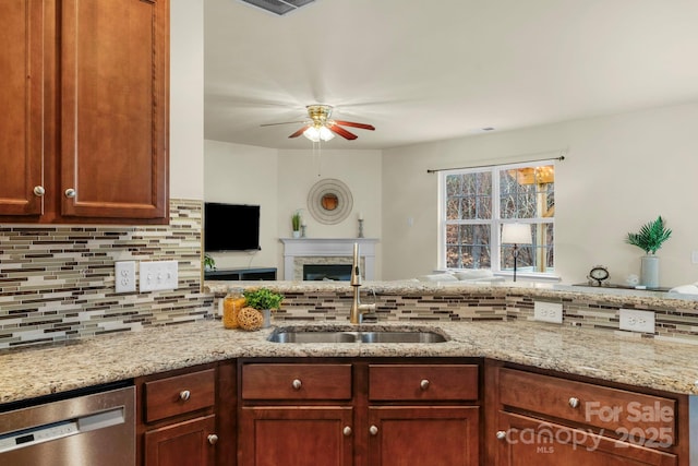 kitchen with sink, light stone counters, dishwasher, ceiling fan, and backsplash