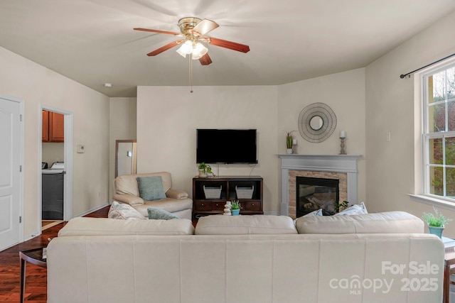 living room featuring dark hardwood / wood-style flooring, washer / dryer, and ceiling fan