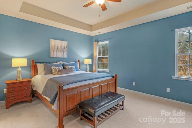 carpeted bedroom featuring ceiling fan and a tray ceiling