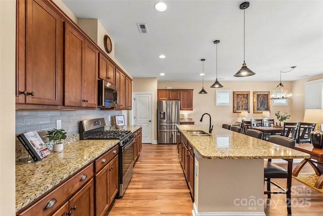 kitchen with a spacious island, a breakfast bar, sink, decorative light fixtures, and stainless steel appliances