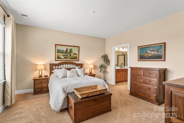 bedroom featuring connected bathroom and light colored carpet