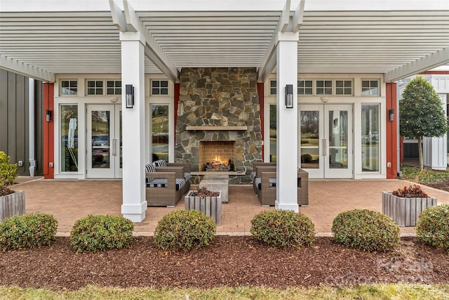 view of patio featuring french doors, an outdoor stone fireplace, and a pergola