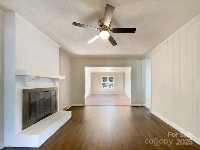 unfurnished living room featuring crown molding, a brick fireplace, dark wood-type flooring, and a textured ceiling