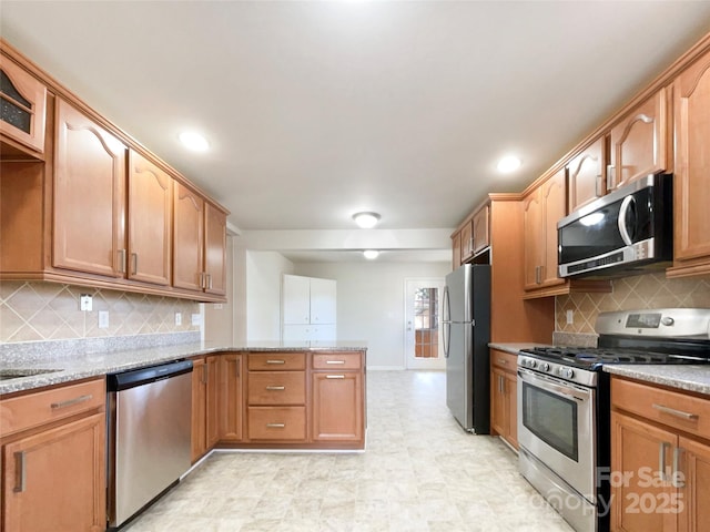 kitchen with light stone counters, backsplash, sink, and appliances with stainless steel finishes