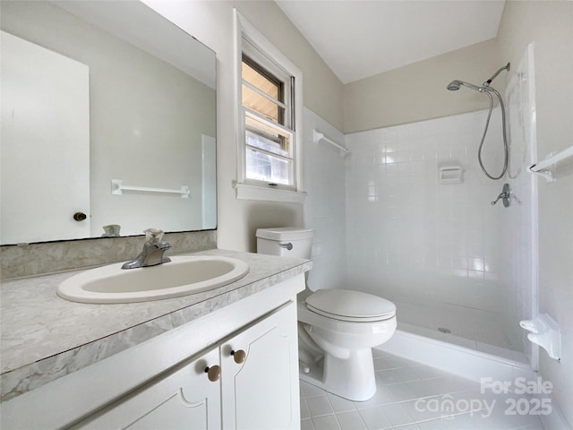 bathroom featuring vanity, tile patterned flooring, toilet, and tiled shower