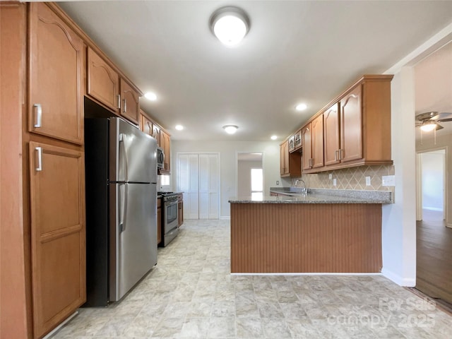 kitchen featuring dark stone countertops, tasteful backsplash, kitchen peninsula, and appliances with stainless steel finishes