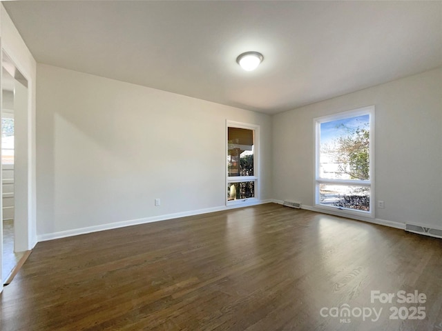 unfurnished room featuring a healthy amount of sunlight and dark hardwood / wood-style flooring