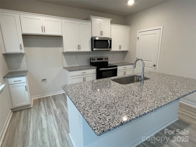 kitchen with stone counters, sink, white cabinets, a kitchen island with sink, and black electric range