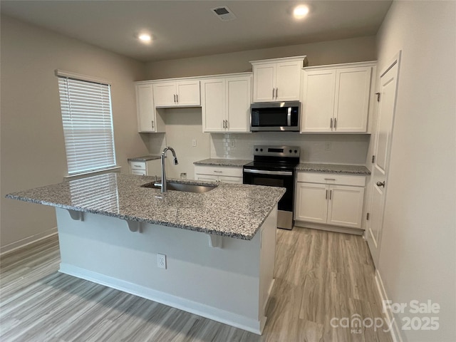 kitchen with stone countertops, sink, white cabinets, and appliances with stainless steel finishes