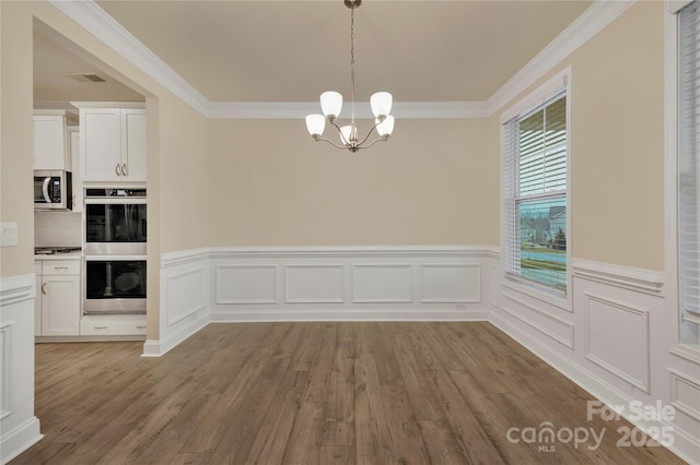 unfurnished dining area with ornamental molding, a chandelier, and wood-type flooring