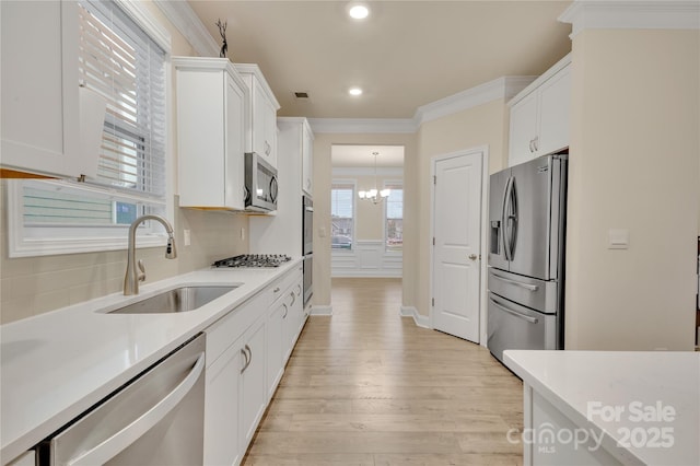 kitchen with crown molding, appliances with stainless steel finishes, sink, and white cabinets