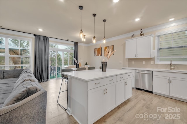 kitchen featuring sink, white cabinetry, hanging light fixtures, stainless steel dishwasher, and ornamental molding