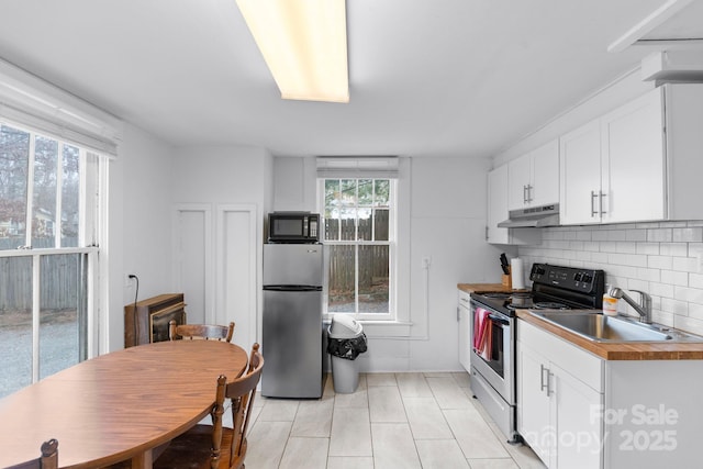 kitchen with butcher block countertops, sink, white cabinetry, and appliances with stainless steel finishes
