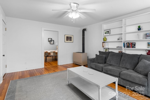 living room featuring hardwood / wood-style flooring, a wood stove, and ceiling fan