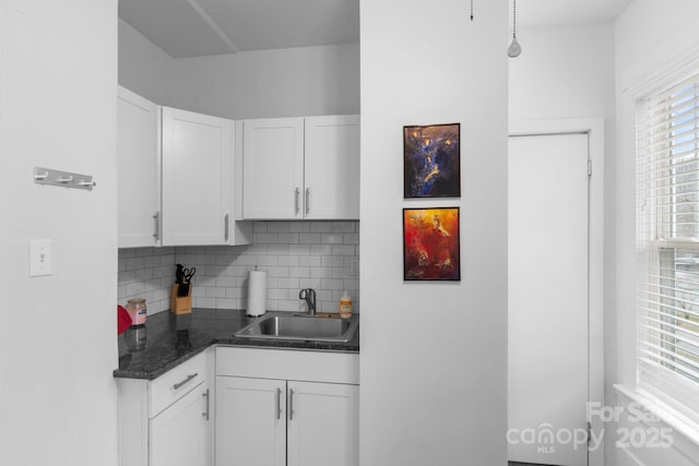 kitchen featuring tasteful backsplash, white cabinetry, hanging light fixtures, and sink