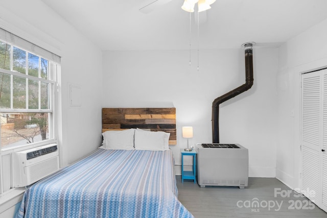 bedroom featuring ceiling fan, wood-type flooring, a closet, and heating unit