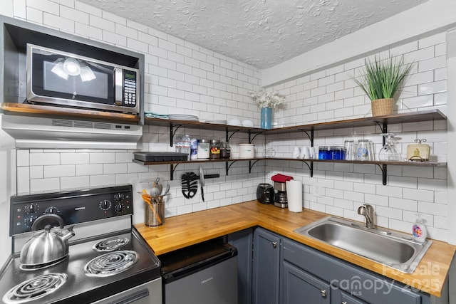 kitchen featuring tasteful backsplash, stainless steel appliances, sink, and butcher block countertops