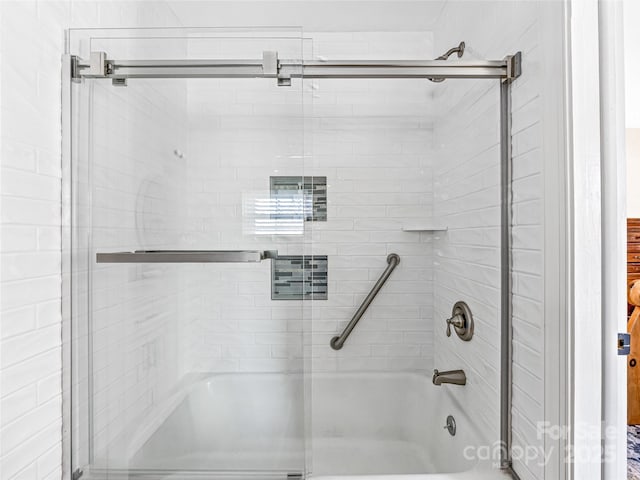 bathroom with bath / shower combo with glass door