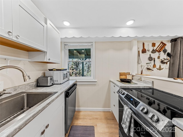 kitchen featuring white cabinetry, sink, stainless steel appliances, and light hardwood / wood-style floors