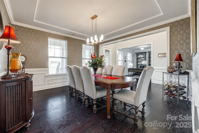 dining space featuring dark wood-type flooring, ornamental molding, and an inviting chandelier