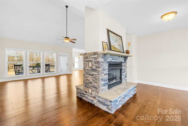 unfurnished living room with hardwood / wood-style flooring, a stone fireplace, a wealth of natural light, and high vaulted ceiling