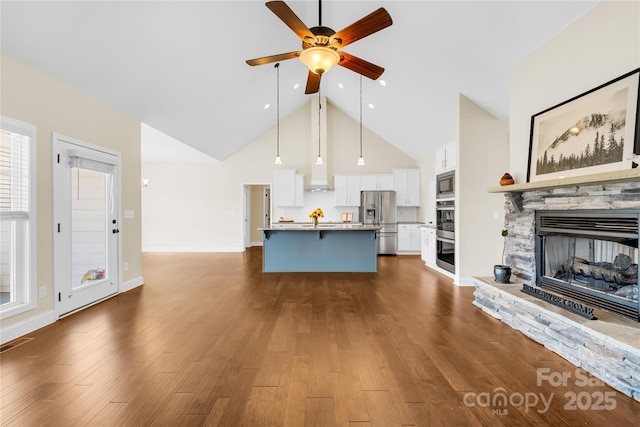 unfurnished living room with dark hardwood / wood-style flooring, a stone fireplace, high vaulted ceiling, and ceiling fan