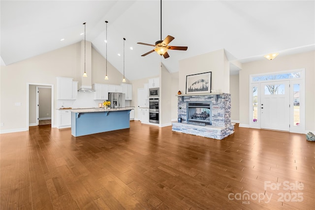 unfurnished living room with wood-type flooring, high vaulted ceiling, ceiling fan, and a fireplace