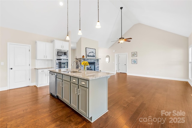 kitchen with sink, white cabinetry, appliances with stainless steel finishes, an island with sink, and light stone countertops