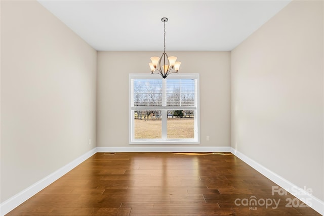 unfurnished dining area featuring an inviting chandelier and hardwood / wood-style flooring