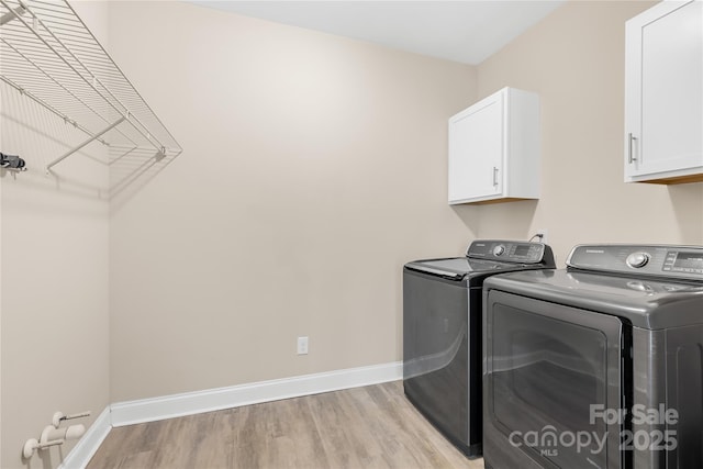 laundry area featuring cabinets, independent washer and dryer, and light wood-type flooring