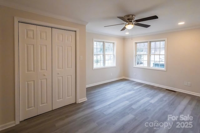 unfurnished bedroom with crown molding, ceiling fan, dark hardwood / wood-style flooring, and a closet