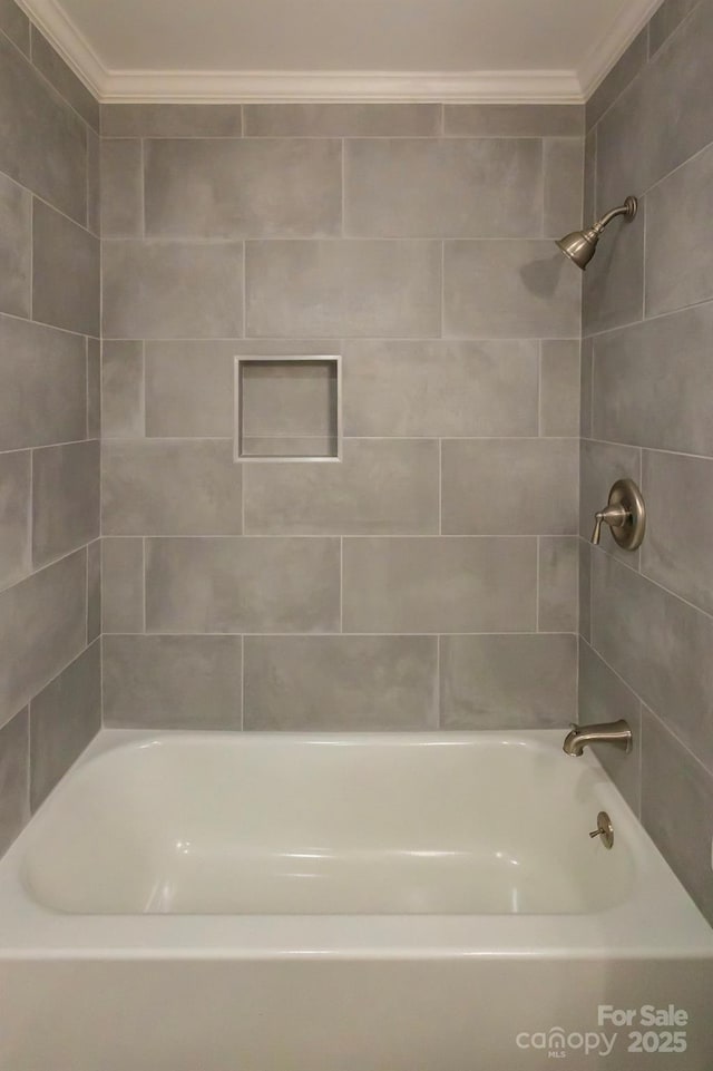 bathroom with tiled shower / bath combo and crown molding