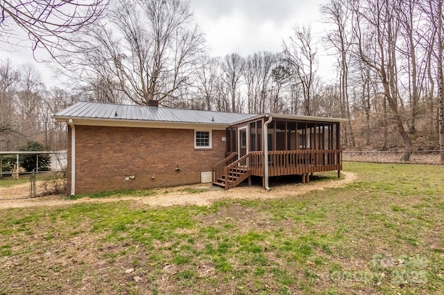 back of property featuring a wooden deck, a yard, and a sunroom