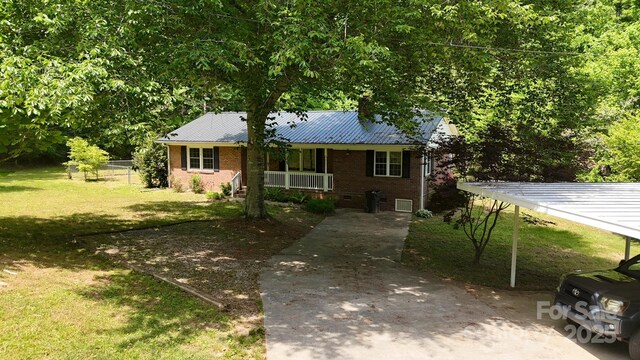 view of front facade with a front lawn, brick siding, covered porch, driveway, and metal roof