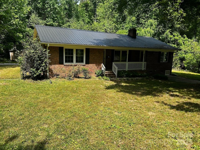 ranch-style house featuring covered porch, a chimney, a front lawn, and metal roof