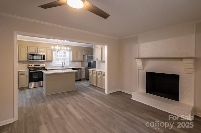 kitchen featuring ornamental molding, wood finished floors, light countertops, a ceiling fan, and stainless steel appliances