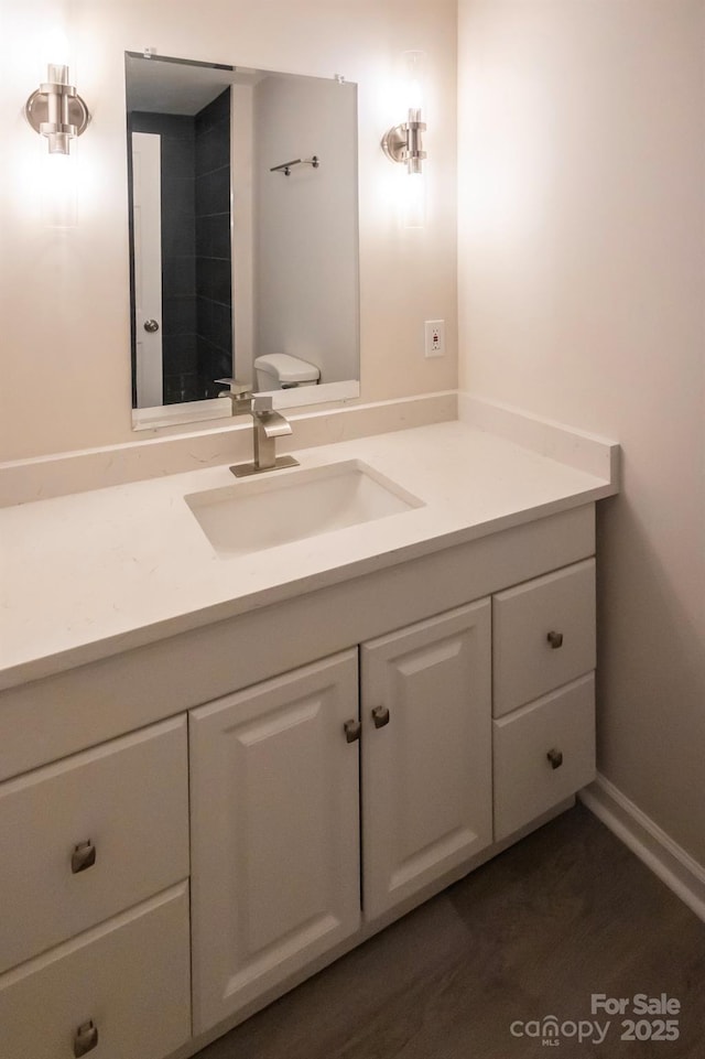 bathroom with vanity, baseboards, and wood finished floors