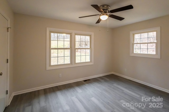 spare room with visible vents, baseboards, dark wood-type flooring, and a healthy amount of sunlight