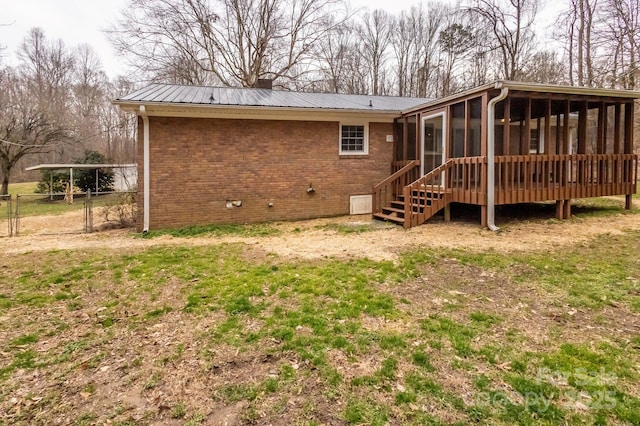 rear view of property featuring fence, brick siding, a sunroom, a chimney, and metal roof