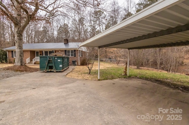 exterior space with a porch, a chimney, metal roof, a front yard, and brick siding