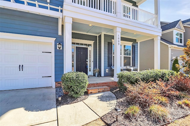 entrance to property featuring a garage, a balcony, and covered porch