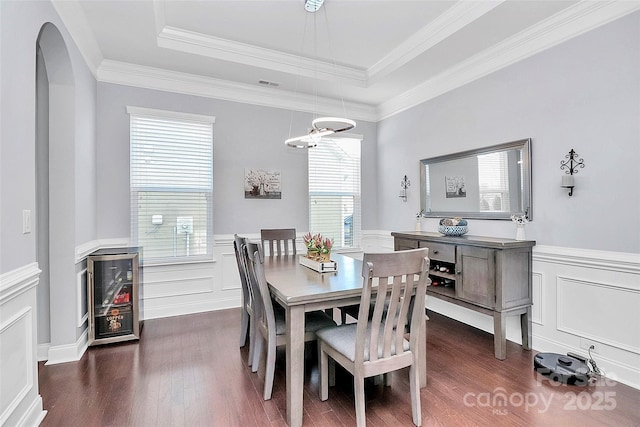 dining space with a raised ceiling, crown molding, and dark hardwood / wood-style floors