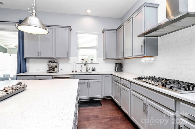 kitchen with appliances with stainless steel finishes, gray cabinets, sink, and wall chimney range hood